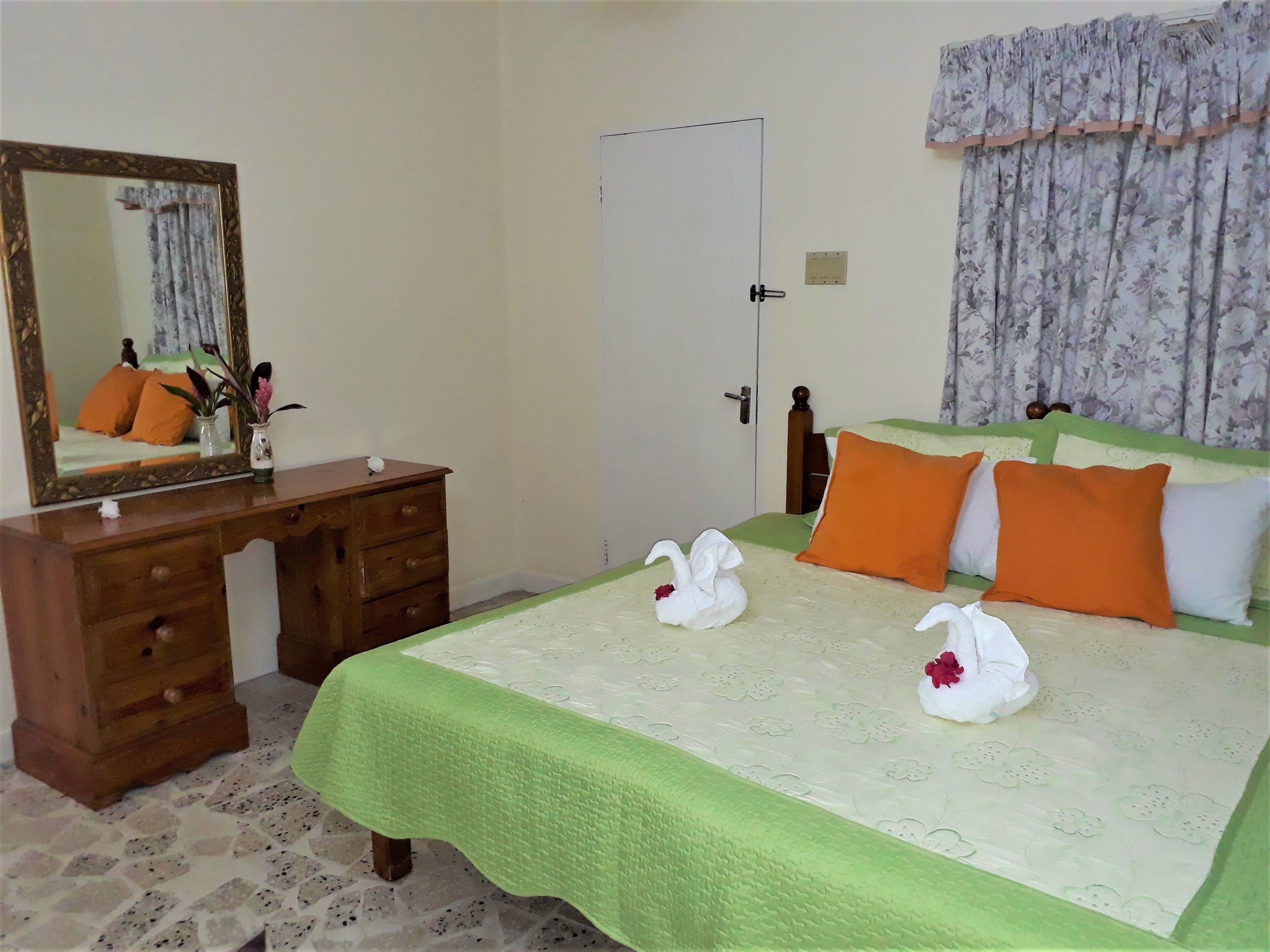 Un dormitorio con cama, cómoda, espejo y puerta.