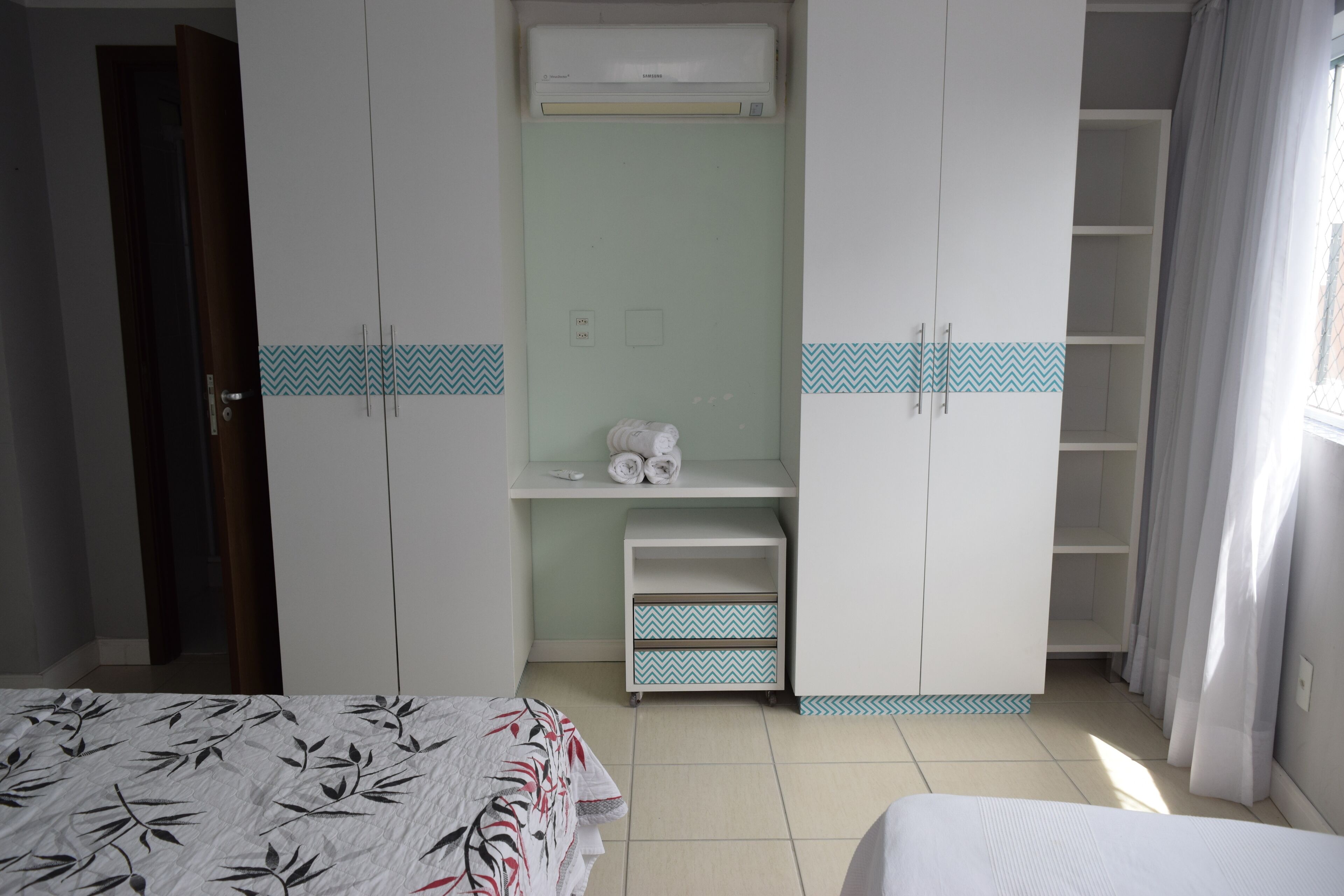 A bedroom with a bed, wardrobe, and a small shelf with towels.