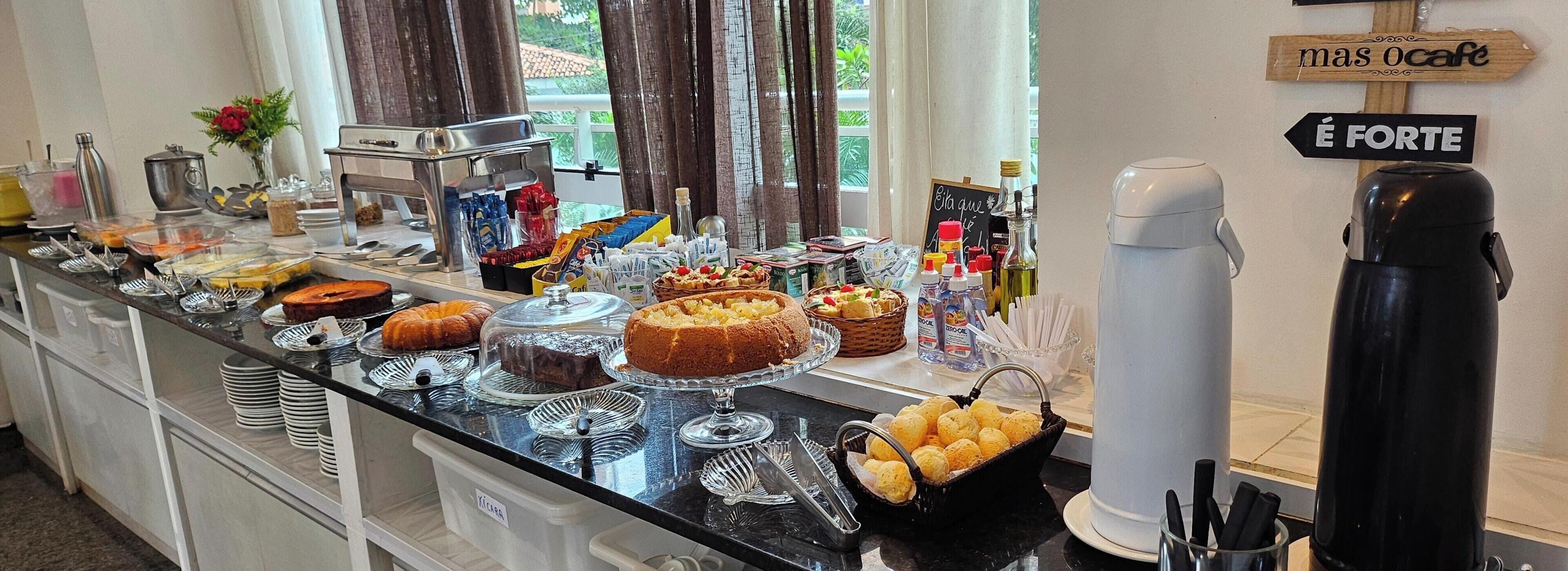 A buffet setup with various food items, a coffee machine, and a sign indicating the strength of coffee.