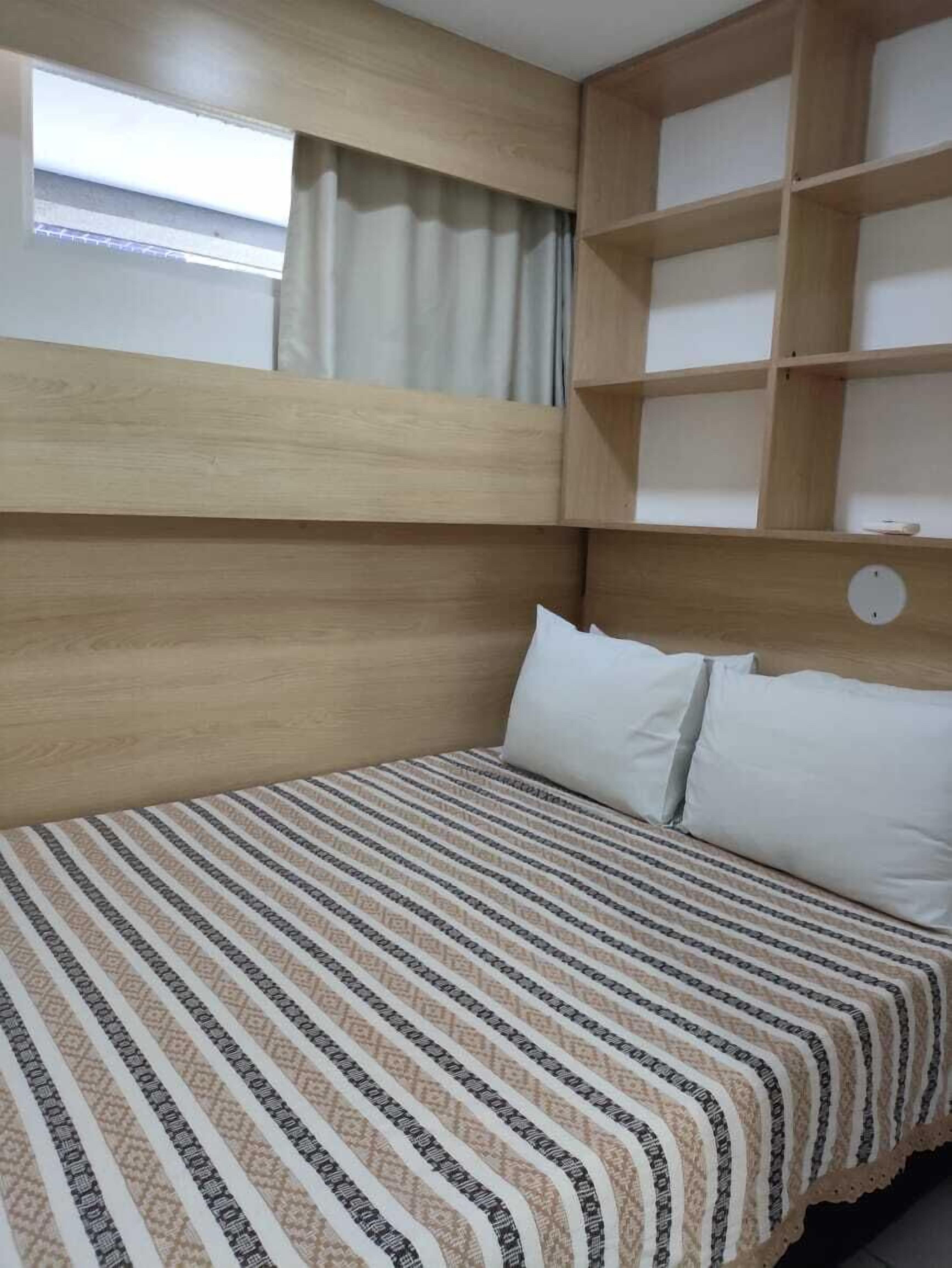 A room with a bunk bed, a window with curtains, and a wooden headboard.
