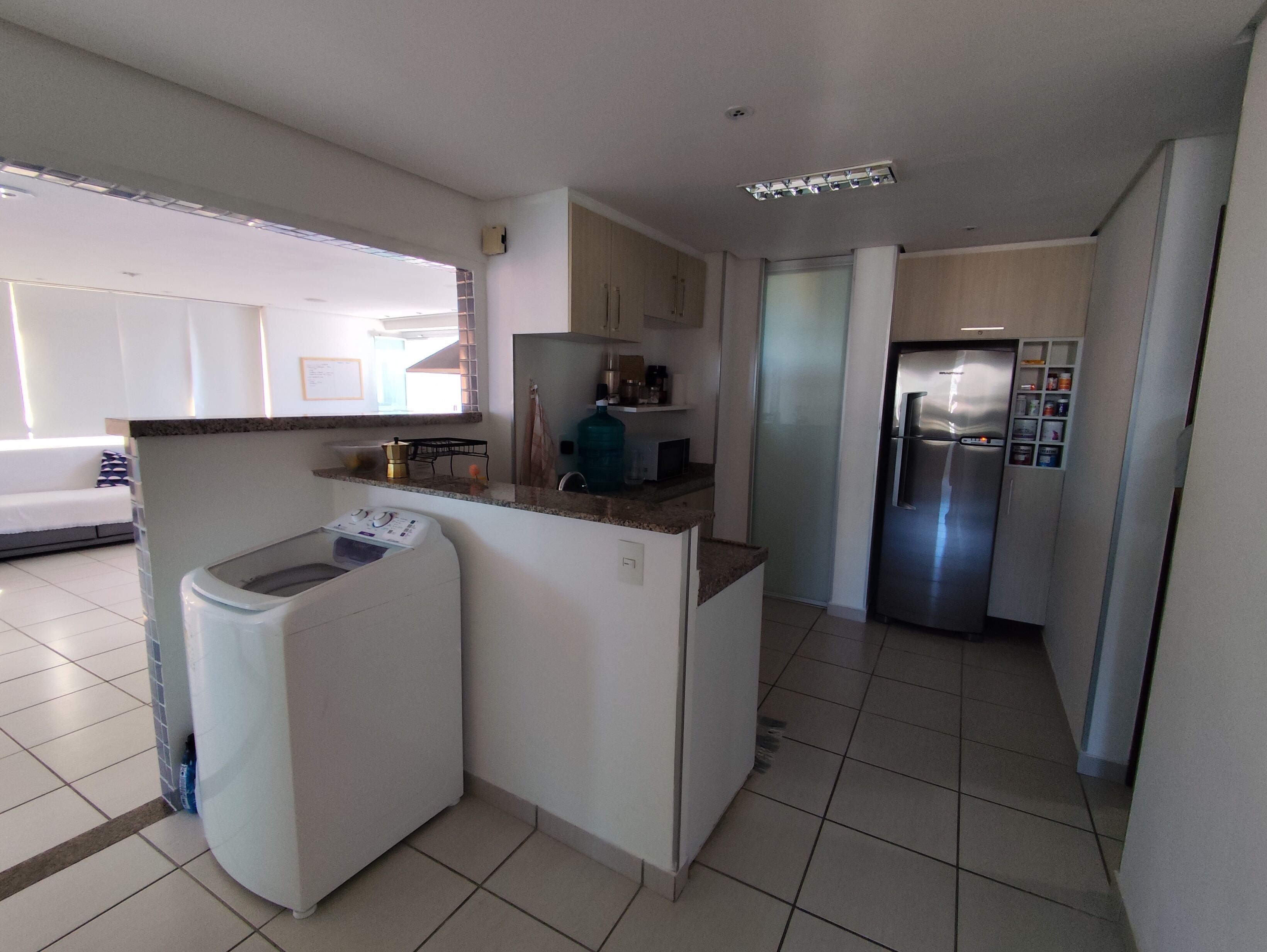 Uma cozinha compacta com máquina de lavar embutida, geladeira e um balcão pequeno.