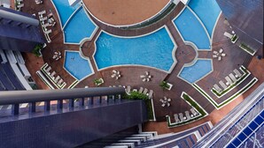 A rooftop pool area with multiple swimming pools, sun loungers, and a central water feature. - Vip Beira Mar Residence (Fortaleza)