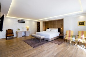 Un dormitorio moderno con una cama grande, mesitas de noche, un escritorio y dos sillones.