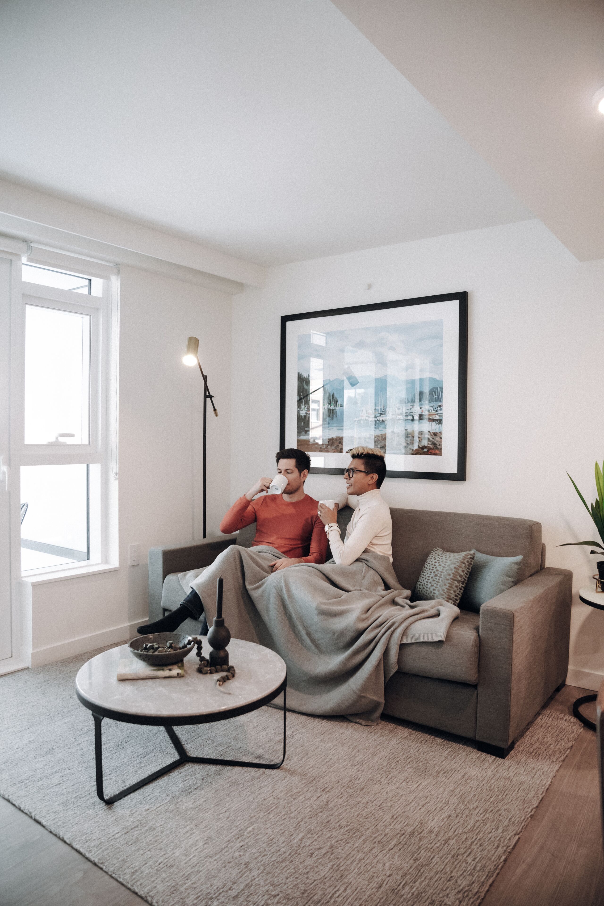 A modern living room with a grey sofa, a round coffee table, and a framed picture on the wall.