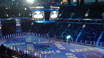 Una arena interior con varios niveles de asientos, una gran pista de hielo central y un marcador.