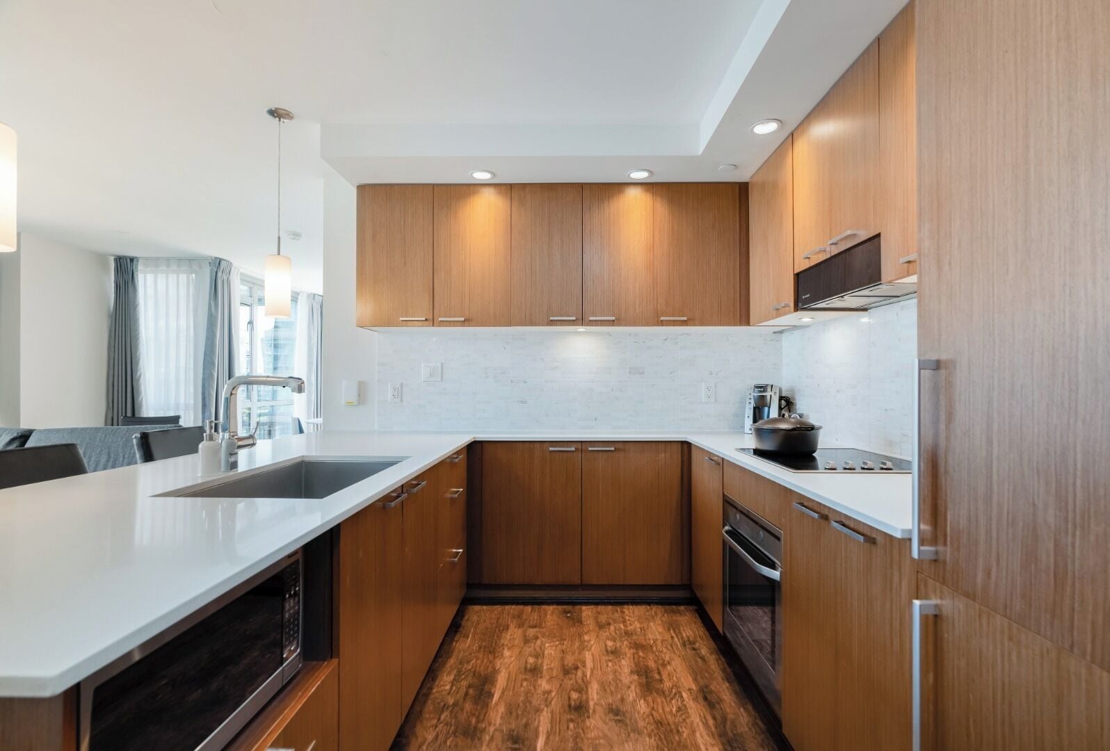 A modern kitchen with wooden cabinets, a white countertop, and built-in appliances.
