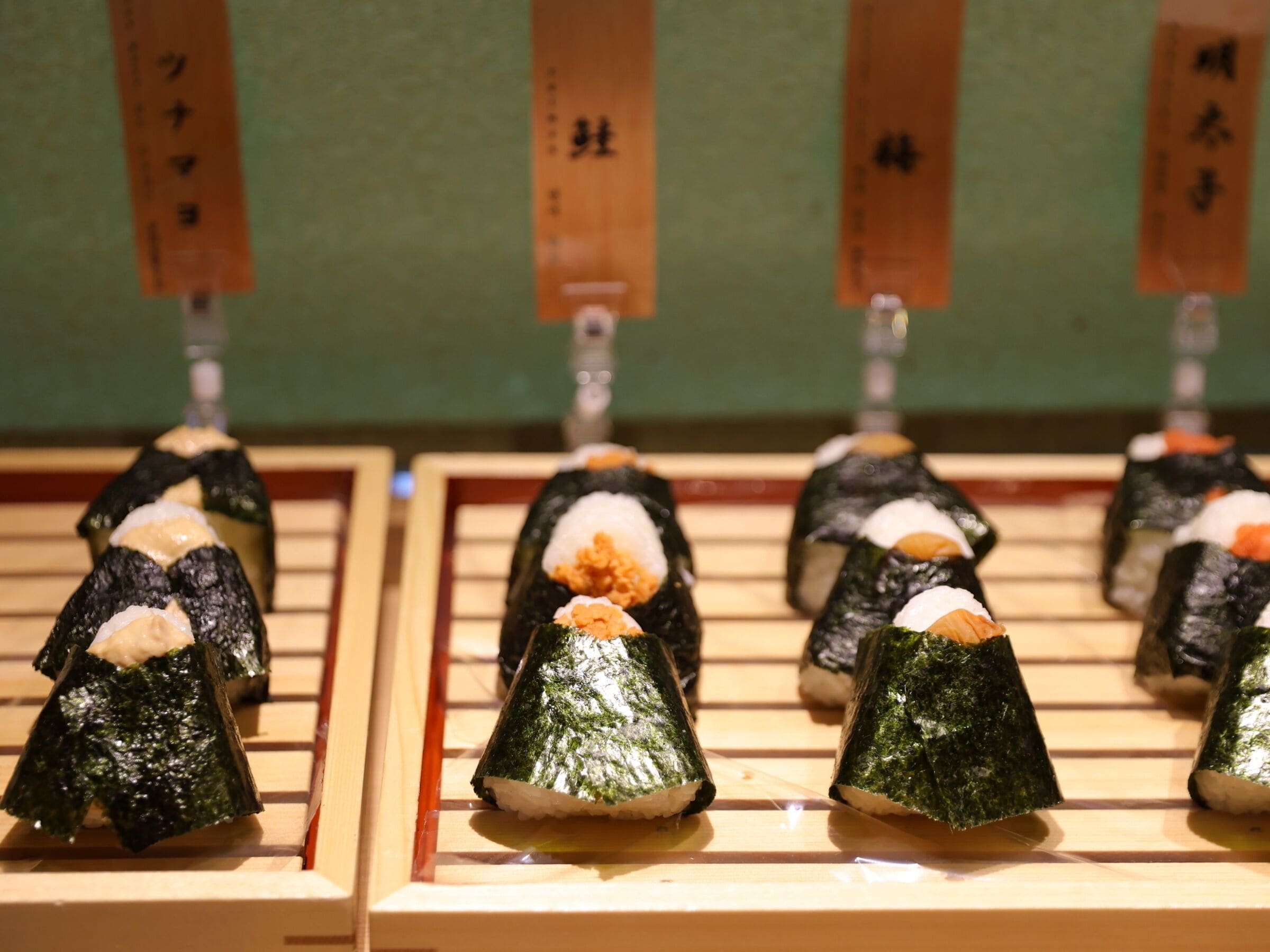 Sushi arranged on wooden trays with labels.
