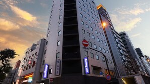 A modern high-rise building with multiple floors, featuring a prominent entrance with a glass facade and a no entry sign. - Dormy Inn Ueno Okachimachi Hot Spring (Tokyo)