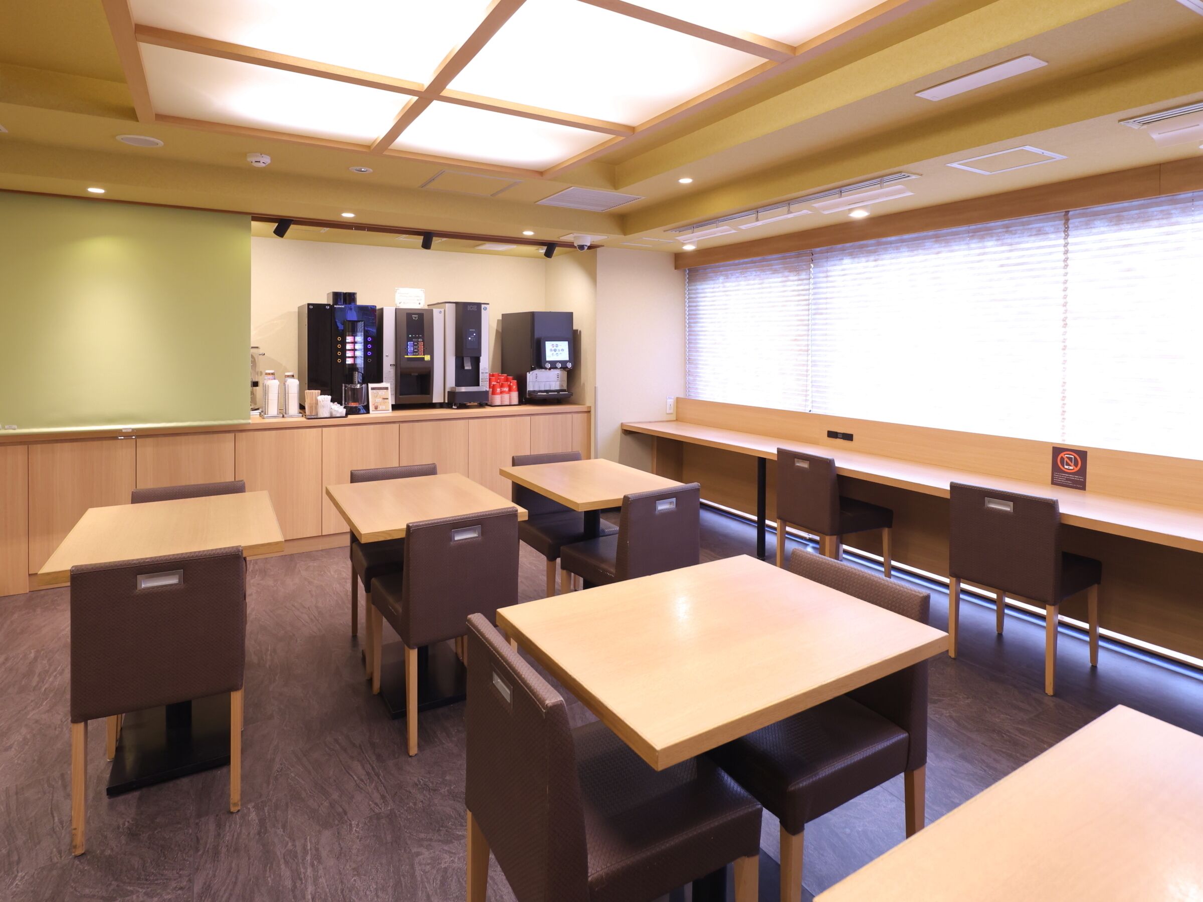 A conference room with tables and chairs, a projector screen, and a coffee station.