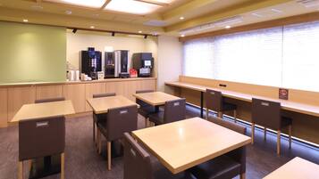 A conference room with tables and chairs, a projector screen, and a coffee station.