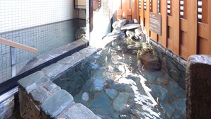 A stone-lined water feature with wooden railings and a tiled wall. - Dormy Inn Ueno Okachimachi Hot Spring (Tokyo)