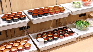 A buffet setup with multiple trays of food items, including bowls of soup, salad, and other dishes. - Dormy Inn Ueno Okachimachi Hot Spring (Tokyo)