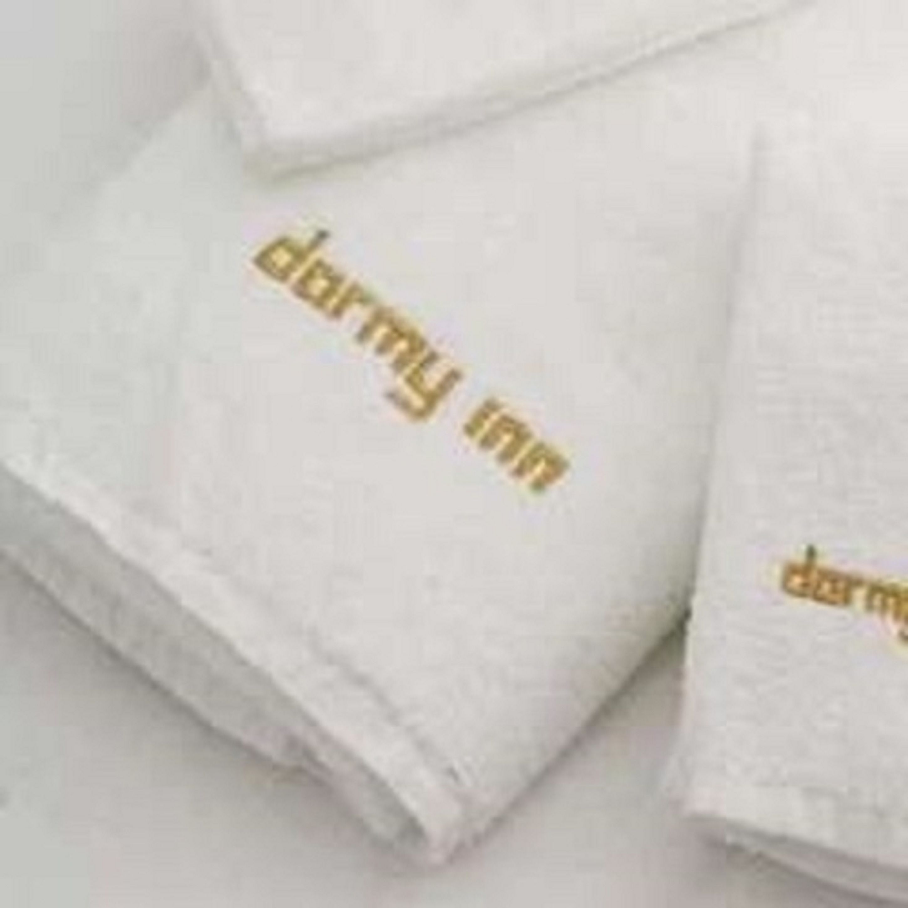A stack of white towels with gold lettering.