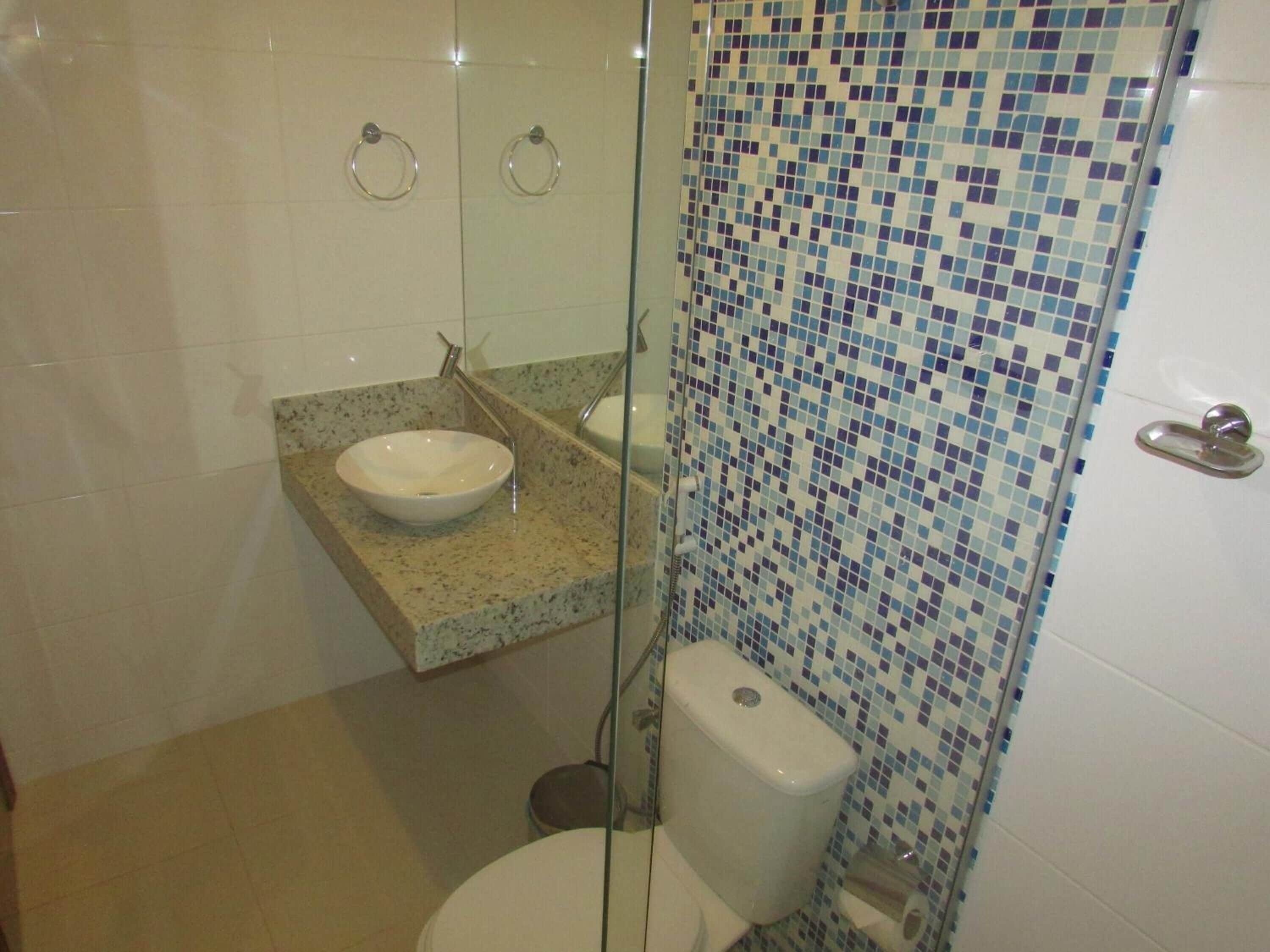 A bathroom with a glass-enclosed shower, a white sink, and a toilet.