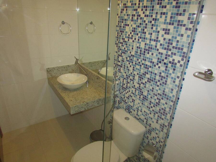A bathroom with a glass-enclosed shower, a white sink, and a toilet.