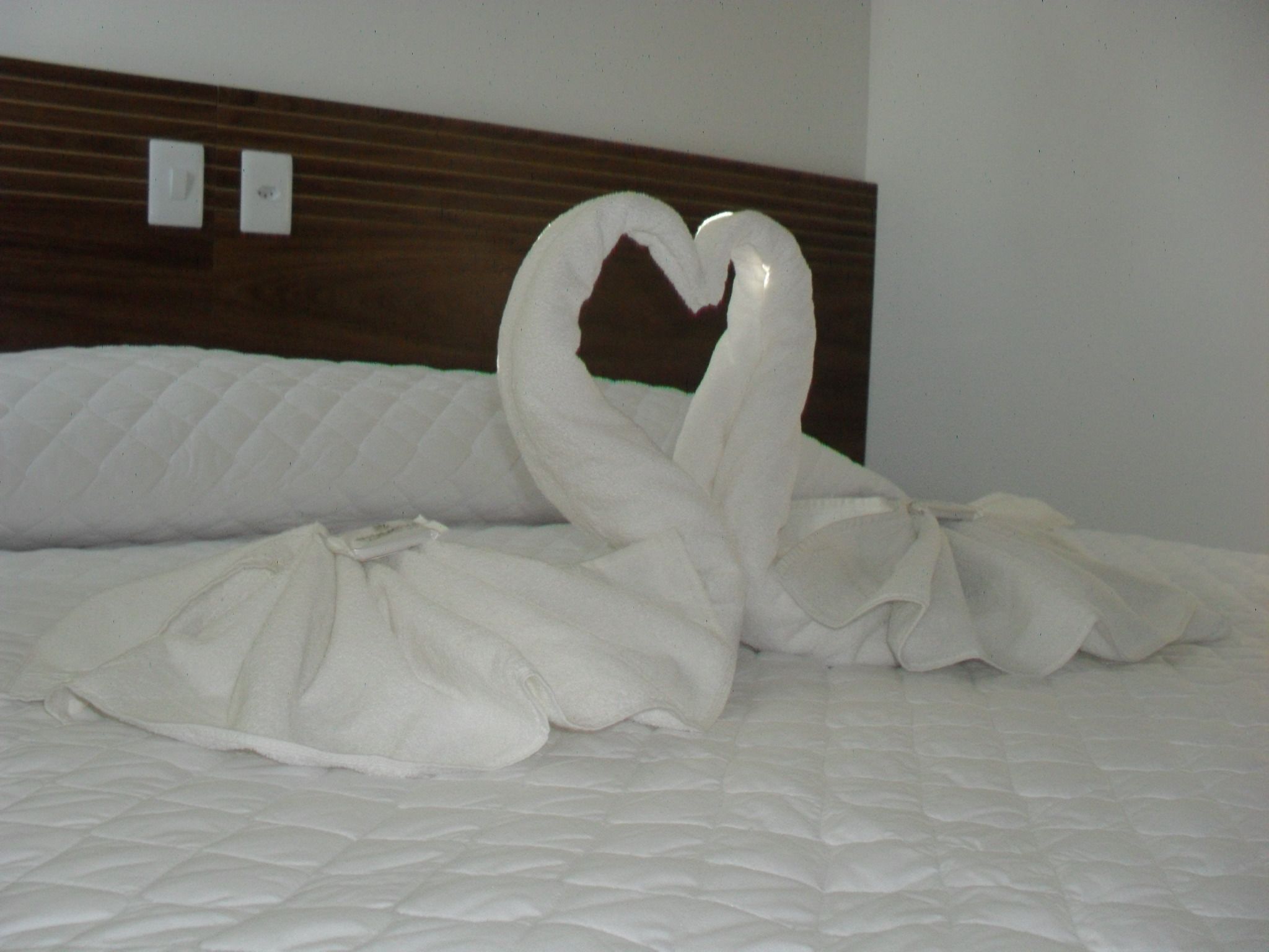 A bed with a heart-shaped towel arrangement.