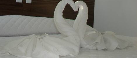 A bed with a heart-shaped towel arrangement.