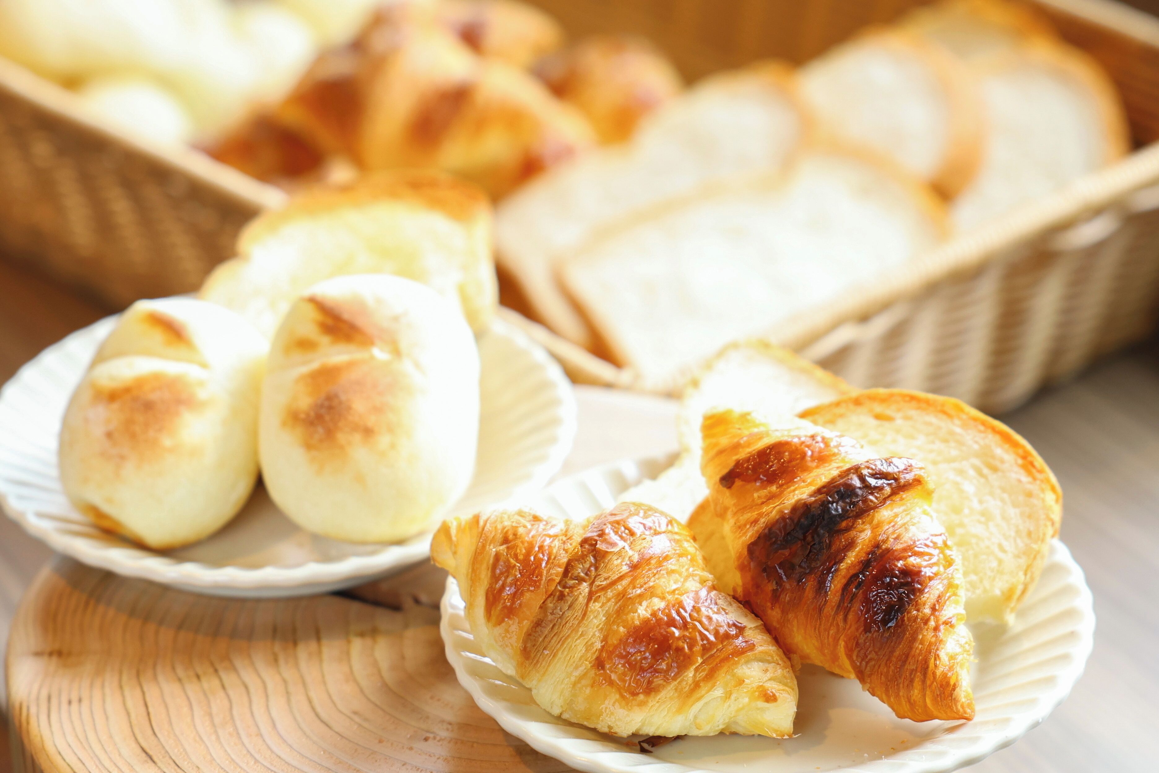 Une variété de produits de boulangerie, notamment du pain et des pâtisseries, présentés sur des assiettes et dans des paniers.