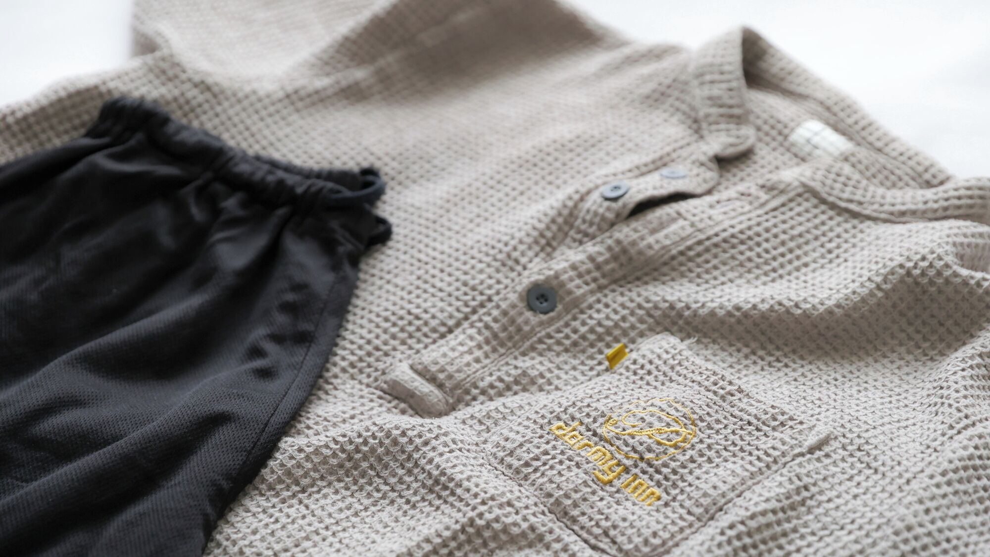 A knitted garment with a button and a small embroidered logo.