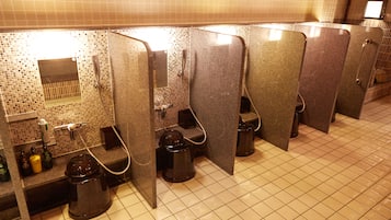 A public restroom with multiple stalls, a tiled floor, and a hand dryer.