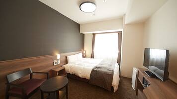 Une chambre d’hôtel avec un lit, une télévision, un bureau, une chaise et une petite table.