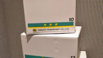Trois boîtes empilées, portant les numéros 10, 12 et 14, et sur lesquelles figurent le texte « YAMATO TRANSPORT CO., LTD. » ainsi qu’une adresse de site web.
