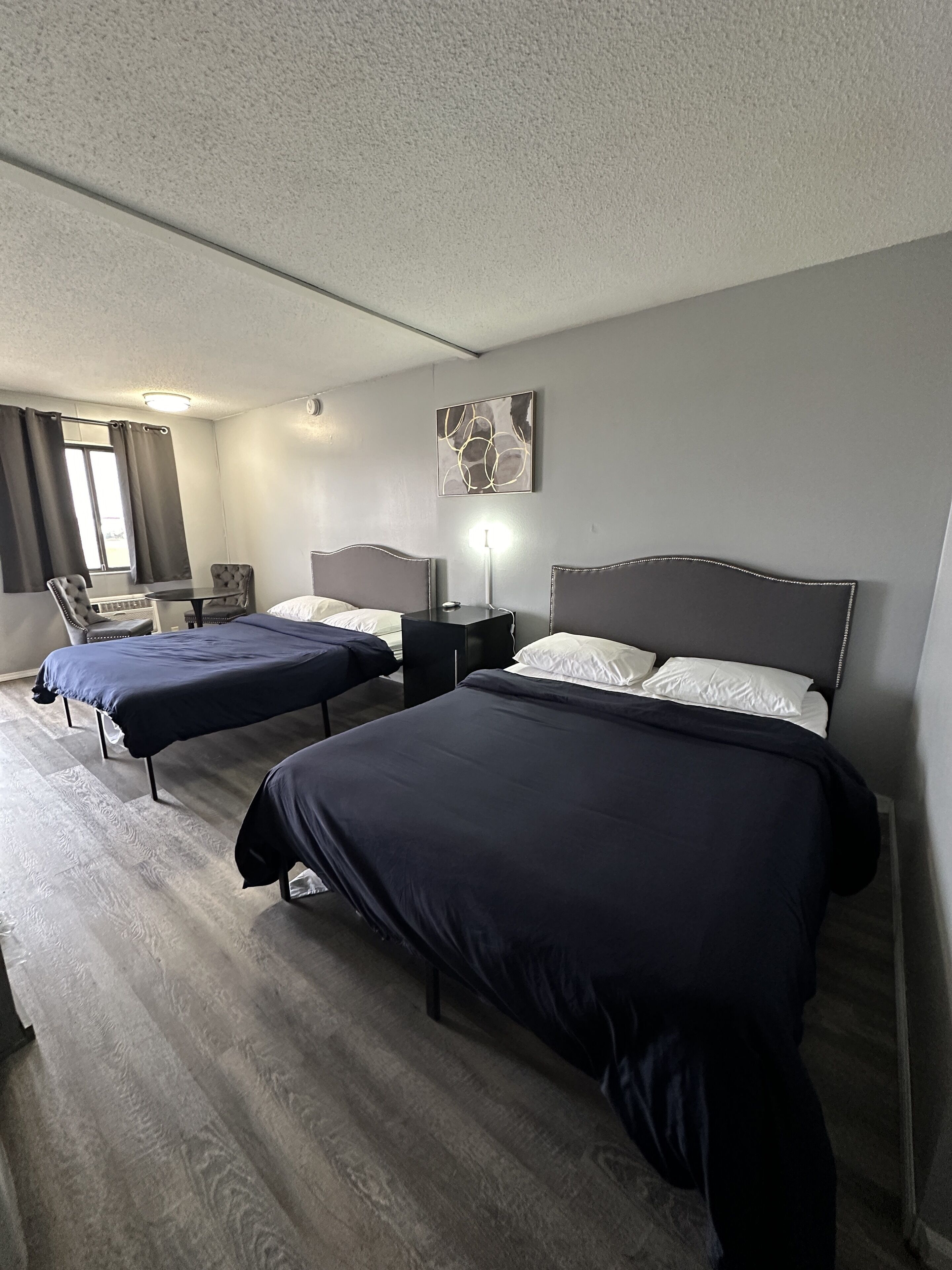 A hotel room with two beds, a desk, and a chair.