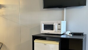 A compact kitchenette with a microwave, a small refrigerator, and a trash bin. - Paxton Inn Motel (Paxton)
