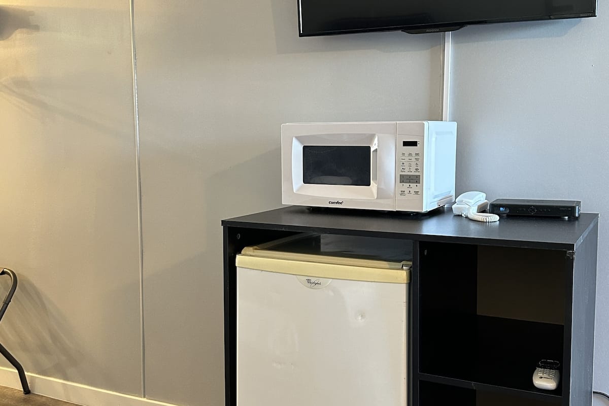 A compact kitchenette with a microwave, a small refrigerator, and a trash bin.