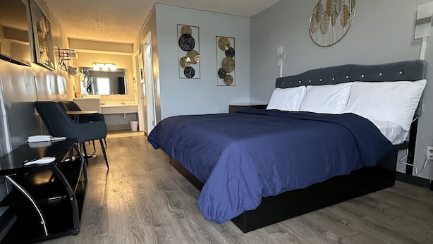 A modern bedroom with a large bed, a desk, and a chair. - Paxton Inn Motel (Paxton)
