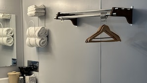 A bathroom with a towel rack, a hanging towel rack, a towel dispenser, a sink, and a small stool. - Paxton Inn Motel (Paxton)