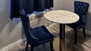 A small, round table with a marble top, flanked by two upholstered chairs with studded details. - Paxton Inn Motel (Paxton)