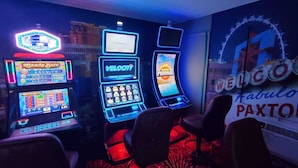 A gaming area with slot machines and a neon sign that reads "Welcome to Fabulous Paxton." - Paxton Inn Motel (Paxton)