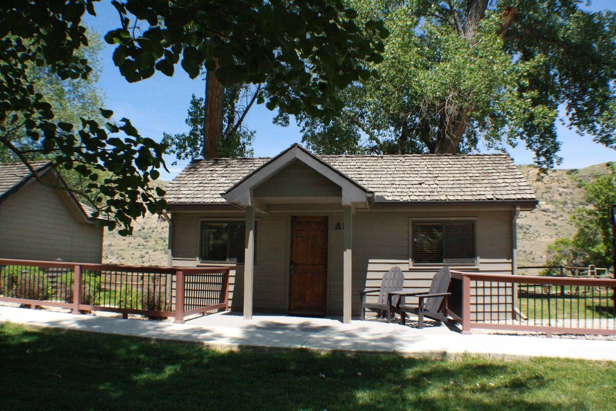 A two-story house with a front porch, a wooden door, and a small patio area with a table and chairs.
