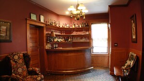 Una zona de bar con estantes de madera, una barra y dos sillas.