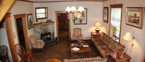 A traditional living room with a stone fireplace, a wooden coffee table, and a patterned sofa.