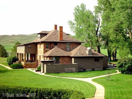 A two-story house with a stone facade, a large front porch, and a well-maintained lawn.