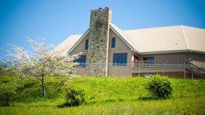 A large stone building with a prominent stone chimney, surrounded by lush greenery and a clear blue sky. - Country Hideaway at Mountain Lakes (Cleveland)