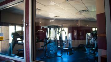 Un gimnasio con equipo de ejercicio, una cinta de correr y un espejo grande.