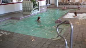 An indoor swimming pool with multiple lanes, a lifeguard station, and a seating area with chairs. - Country Hideaway at Mountain Lakes (Cleveland)