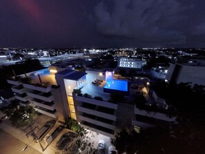 Un edificio moderno con piscina en la azotea y zona de estar al aire libre.