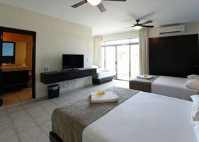 A hotel room with a bed, a desk with a television, a bathroom, and a view of the outside.