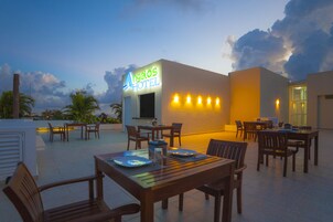A rooftop dining area at the hotel with tables and chairs, a neon sign, and a view of the sky.