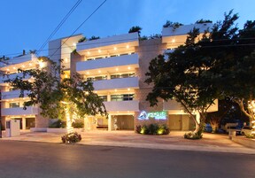 A modern hotel with multiple floors, a prominent neon sign, and well-lit exterior.