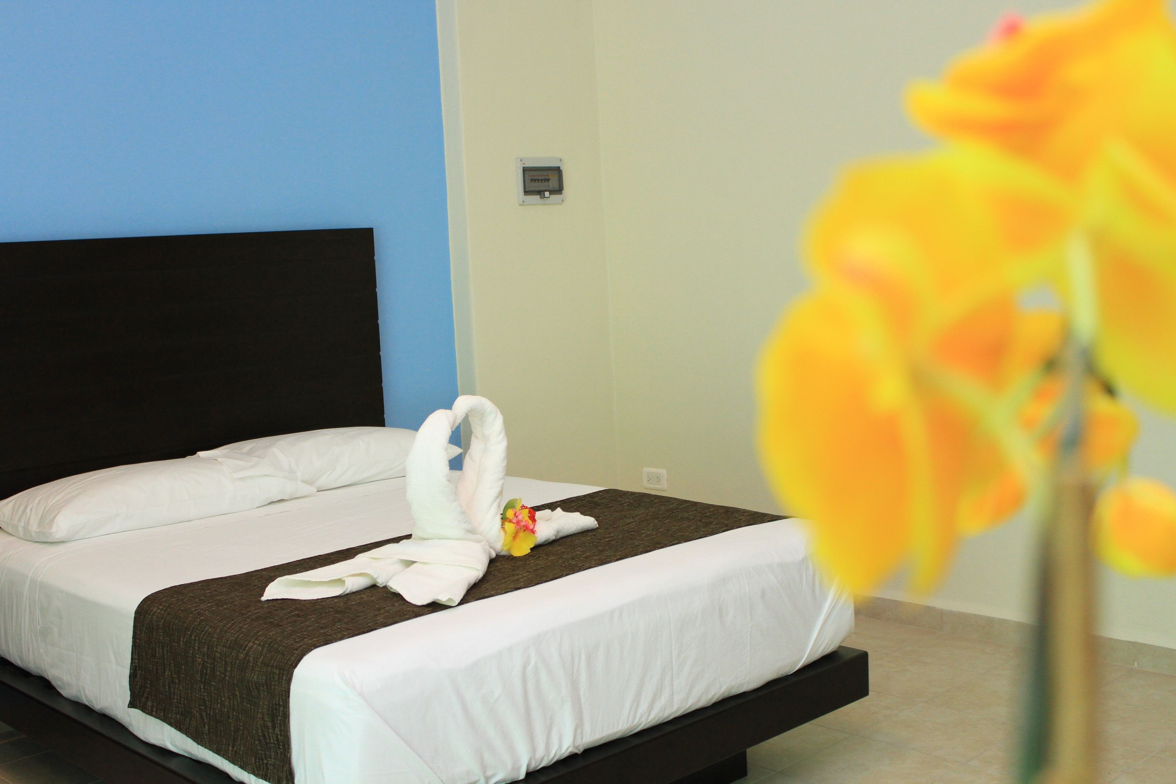 Una habitación de hotel con una cama, un panel de control en la pared y una flor en un jarrón.
