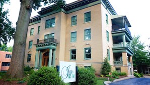 A multi-story building with a green facade, a prominent entrance with a porch, and a sign indicating the address. - Inn at 835 Boutique Hotel (Springfield)