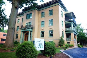 A multi-story building with a green facade, a prominent entrance with a porch, and a sign indicating the address. - Inn at 835 Boutique Hotel (Springfield)