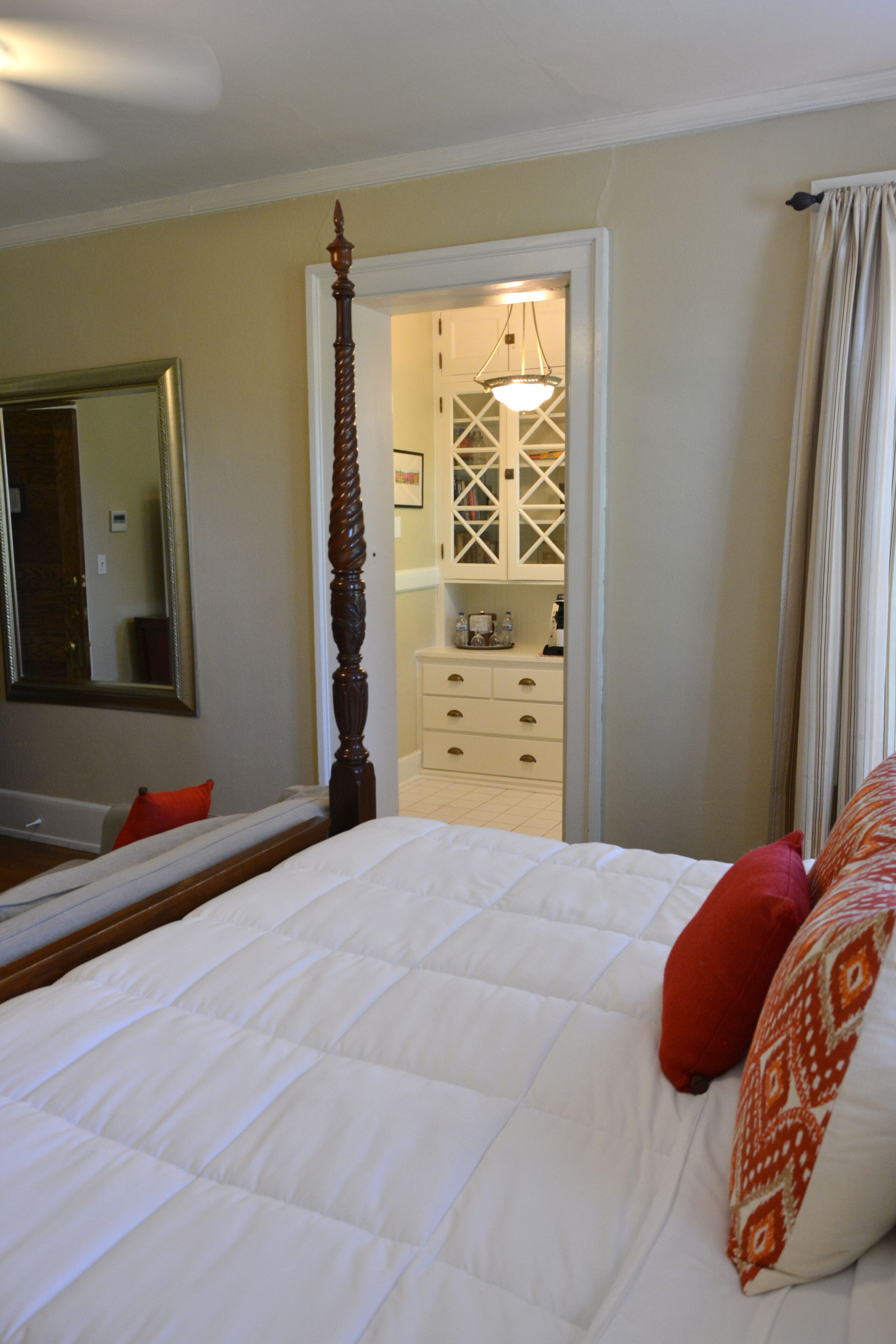 A bedroom with a four-poster bed, a mirror, and a walk-in closet.