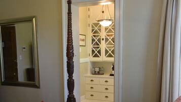 A bedroom with a four-poster bed, a mirror, and a walk-in closet.