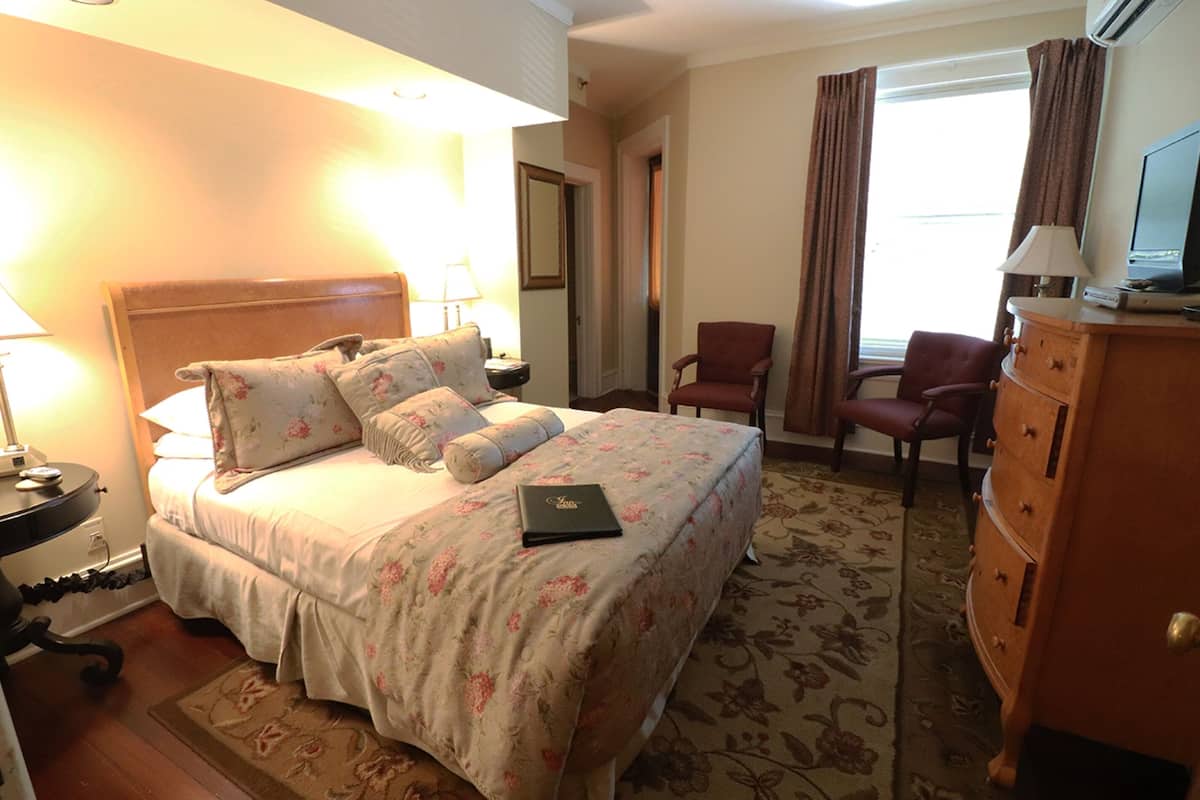 Habitación de hotel con cama, escritorio, silla, cómoda y televisor.